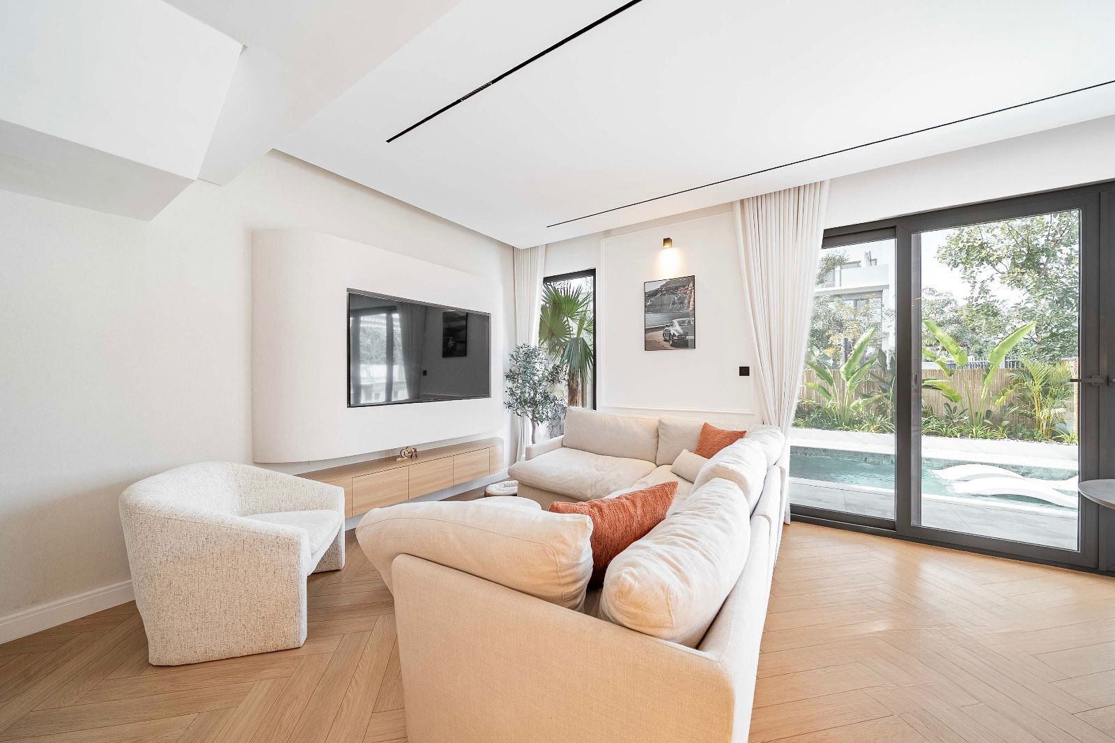 Living room with curved TV wall and pool view